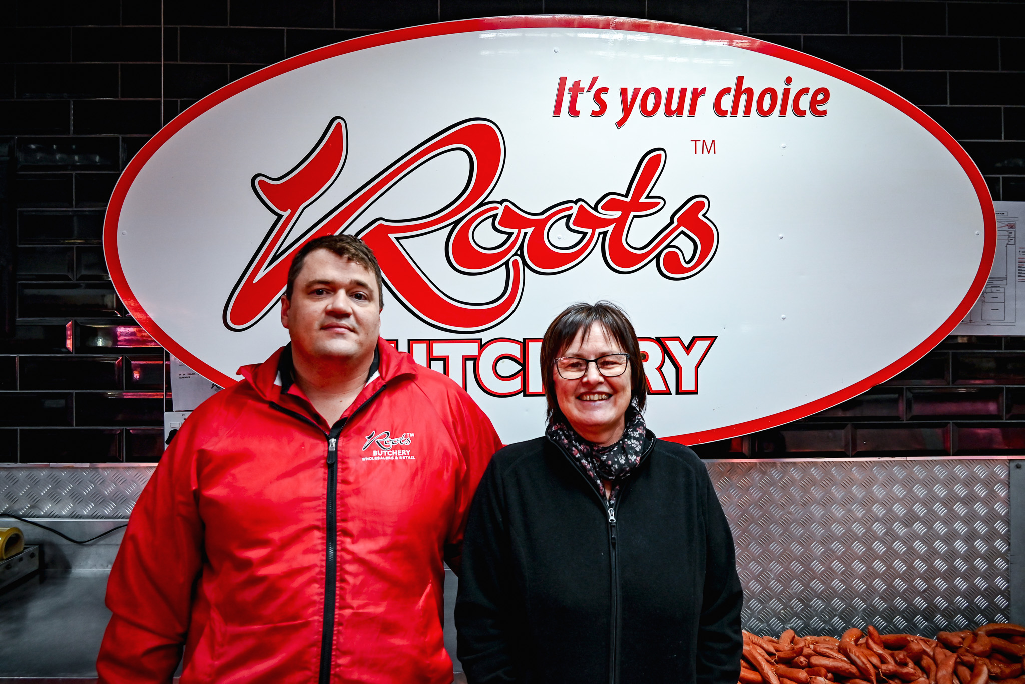 Roots Vryheid management, Jan van Gent and Nettie van Rooyen, in front of the Roots Butchery sign